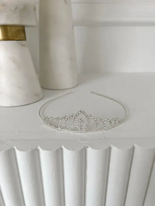 Teter Warm Millie Rhinestone Tiara displayed on a white shelf with elegant marble decor in the background.