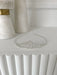 Teter Warm Millie Rhinestone Tiara displayed on a white shelf with elegant marble decor in the background.