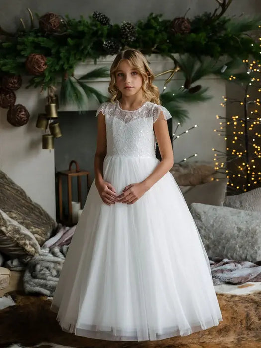 Teter Warm Nadia off-white lace communion dress worn by a girl standing in a cozy living room.