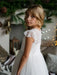 Teter Warm Nadia off-white lace communion dress worn by a girl standing indoors near festive decor.