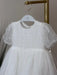 Teter Warm Perla off-white sequin baptism dress with sheer sleeves hanging on a rack.