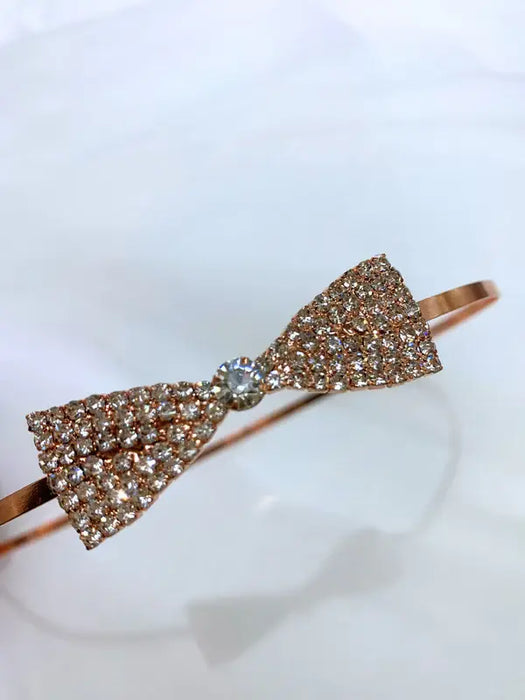 Teter Warm Polli Rose Gold Headband with crystal bow detail on a plain background.
