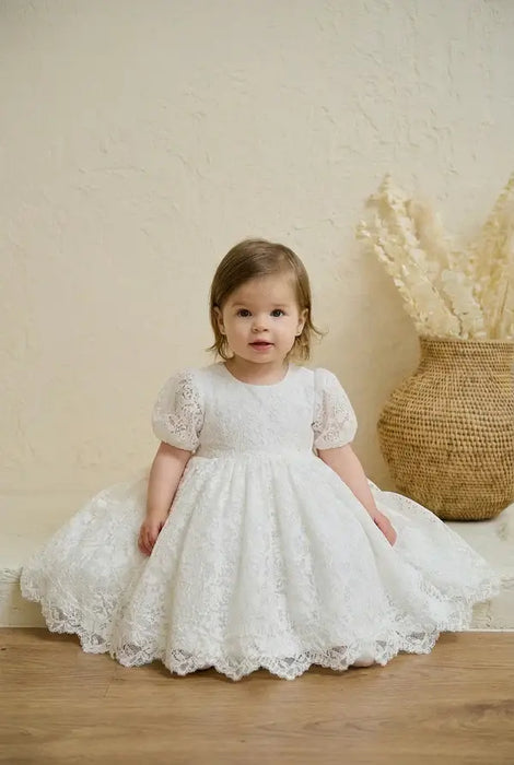 Teter Warm Precious Lace Baptism Dress shown on a toddler sitting indoors with a neutral background.