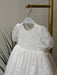 Teter Warm Precious Lace Baptism Dress with floral lace design displayed on a hanger indoors.