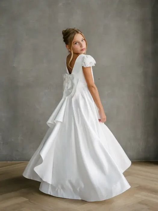Teter Warm Quinn Satin Communion Dress with lace sleeves shown on a young girl standing indoors.