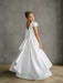 Teter Warm Quinn Satin Communion Dress with lace sleeves shown on a young girl standing indoors.
