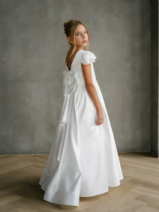 Teter Warm Quinn Satin Communion Dress shown on a young girl with lace sleeves and a large back bow
