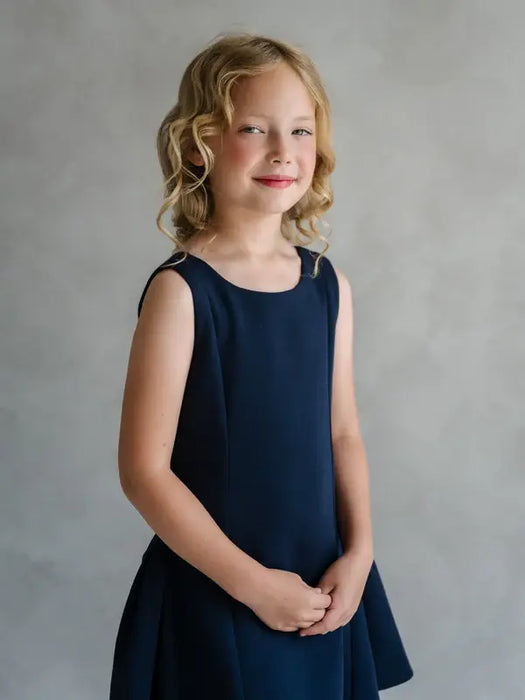Teter Warm Rees dark sleeveless party dress worn by a smiling girl against a neutral background.