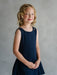 Teter Warm Rees dark sleeveless party dress worn by a smiling girl against a neutral background.