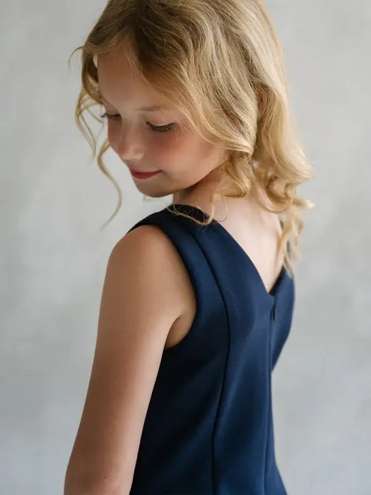 Teter Warm Reese dark sleeveless party dress shown on a young girl with blonde hair, rear view.
