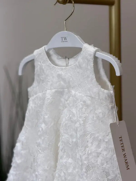 Teter Warm Rosalyn off-white floral baptism dress hanging on a white hanger against a neutral background.