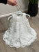 Teter Warm Rosalyn off-white floral lace baptism dress displayed on a hanger on wood floor.