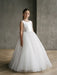 Teter Warm Shelly Satin Bow Communion Dress shown on a young girl standing indoors against a gray wall.
