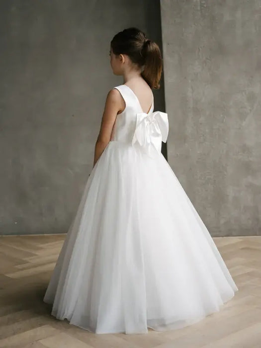 Teter Warm Shelly Satin Bow Communion Dress shown on a girl standing indoors with a large white bow