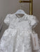 Teter Warm Sia off-white floral lace baptism dress hanging on a hanger with tag visible.
