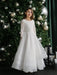 Teter Warm Taula Lace Communion Dress with long lace sleeves worn by a girl standing by a decorated Christmas tree.