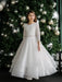 Teter Warm Taula Lace Communion Dress worn by a girl standing in front of a decorated Christmas tree.