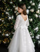 Teter Warm Taula lace communion dress with satin bow, shown on a young girl near a decorated Christmas tree.