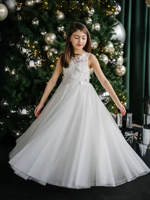 Teter Warm Thea off-white communion dress worn by a girl standing by a decorated Christmas tree.