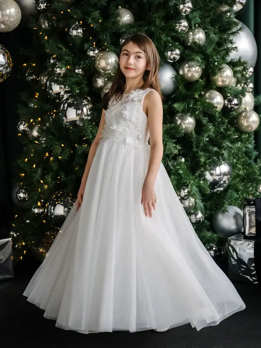 Teter Warm Thea off-white communion dress worn by a girl standing in front of a decorated Christmas tree.