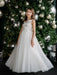 Teter Warm Thea off-white communion dress worn by a girl standing in front of a decorated Christmas tree.