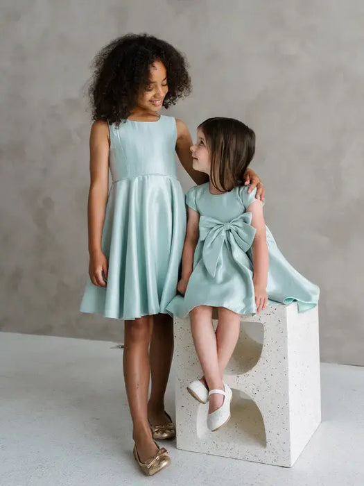 Teter Warm Tiffany Blue sleeveless party dress shown on two young girls in a bright studio setting.