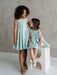Teter Warm Tiffany Blue sleeveless party dress shown on two young girls in a bright studio setting.