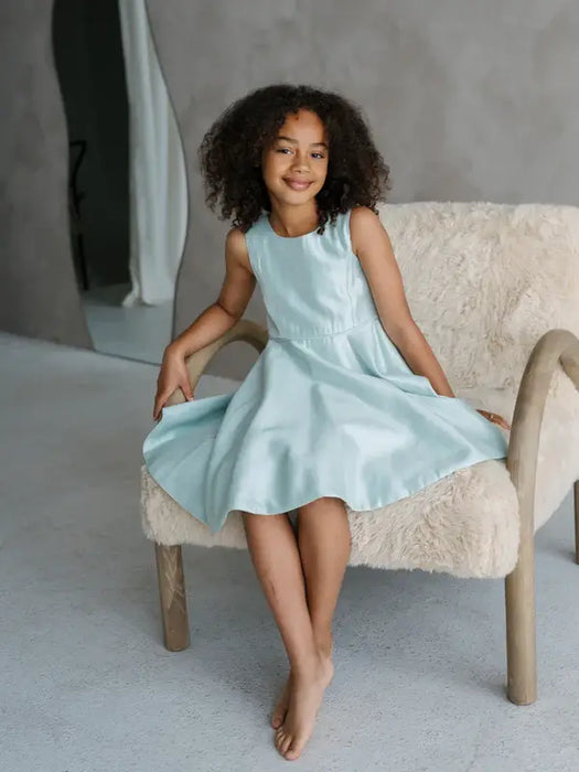 Teter Warm Tiffany Blue Sleeveless Party Dress worn by a girl sitting on a cozy chair indoors.