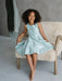 Teter Warm Tiffany Blue Sleeveless Party Dress worn by a girl sitting on a cozy chair indoors.