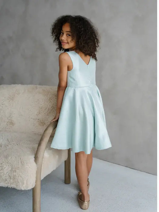 Teter Warm Tiffany Blue sleeveless party dress worn by a girl standing beside a chair indoors.