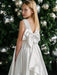 Teter Warm Tori off-white lace communion dress with large back bow, worn by girl in front of decorated tree.