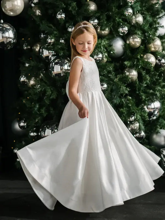 Teter Warm Tori off-white lace communion dress worn by a girl twirling in front of a Christmas tree.