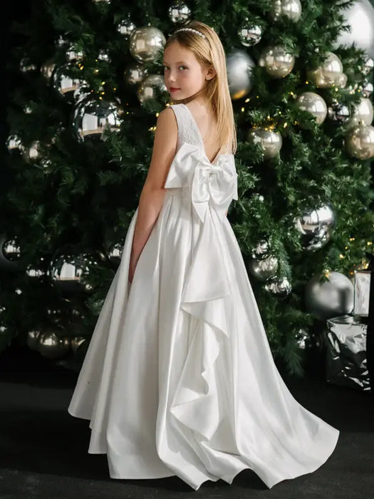 Teter Warm Tori off-white lace communion dress shown on a young girl in front of a decorated tree.