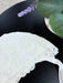 Teter Warm Ultra Soft Baby Bonnet in white lace displayed on a black tabletop near a plant.