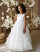 Teter Warm Winniw Off-White Communion Dress worn by a girl standing among white floral decor.