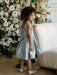 Teter Warm Zelda Blue Party Dress worn by a child standing near a white sofa and floral backdrop.