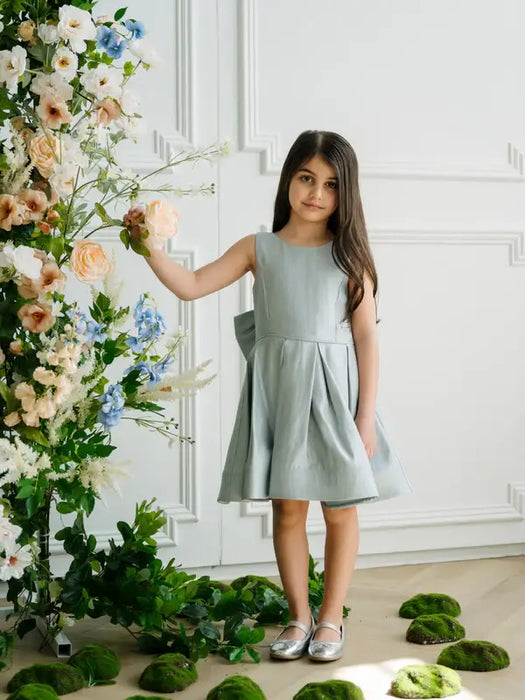 Teter Warm Zelda Blue Party Dress worn by a young girl standing by floral decorations indoors.