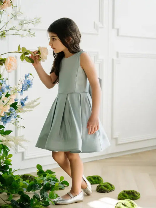 Teter Warm Zelda Blue Party Dress shown on a young girl indoors, smelling flowers.