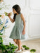 Teter Warm Zelda Blue Party Dress shown on a young girl indoors, smelling flowers.