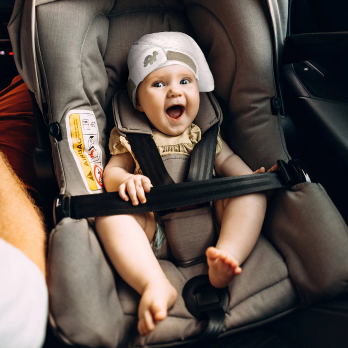 Baby in car seat wearing Tortle Air Turtle Trot repositioning beanie