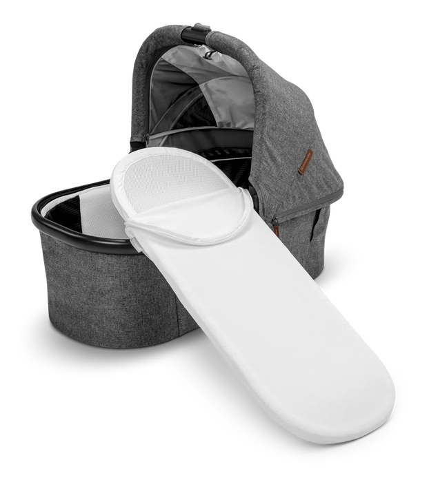 Uppababy bassinet cover in white displayed on a grey bassinet against a plain background.