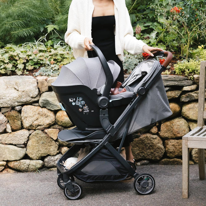 UPPAbaby MINU V3 adapter with MESA car seat attached to stroller outdoors with a person standing nearby.