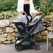 UPPAbaby MINU V3 adapter with MESA car seat attached to stroller outdoors with a person standing nearby.