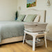 Modern bedside bassinet with mesh sides and storage shelf in a cozy bedroom