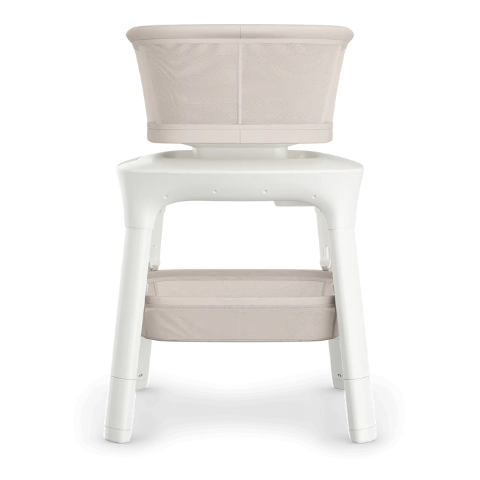 Modern beige mesh baby bassinet with white frame and lower storage shelf
