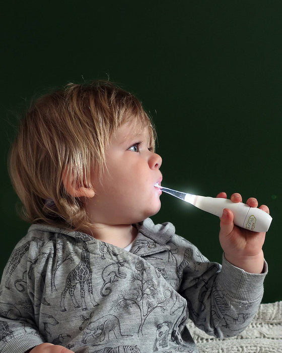 Tickle Tooth Sonic Toothbrush held by a young child, brushing teeth against a dark background.