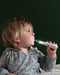 Tickle Tooth Sonic Toothbrush held by a young child, brushing teeth against a dark background.